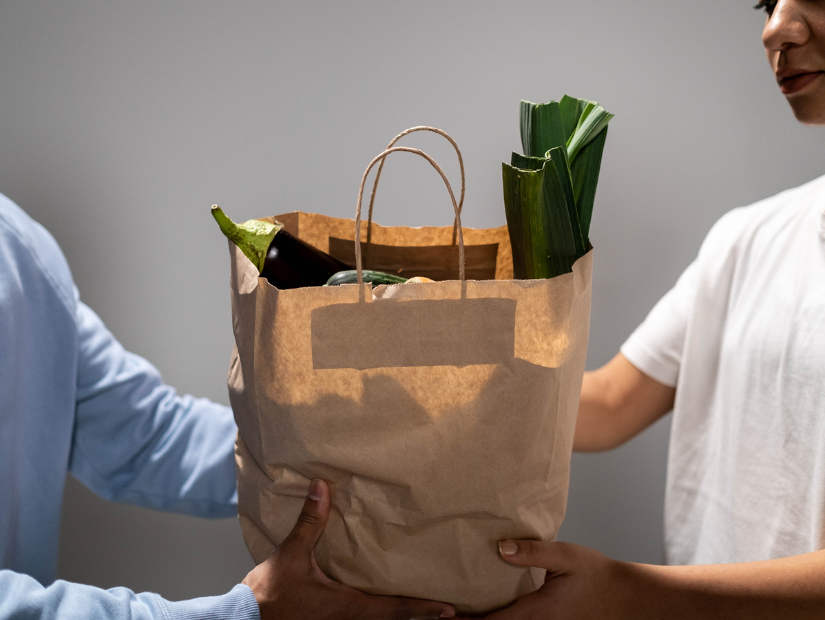 person handing grocery bag to another person
