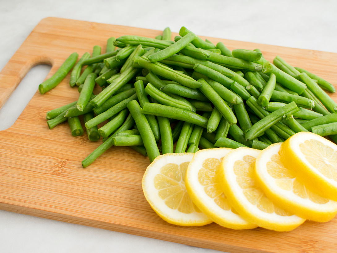 cutting board with green beans and lemon