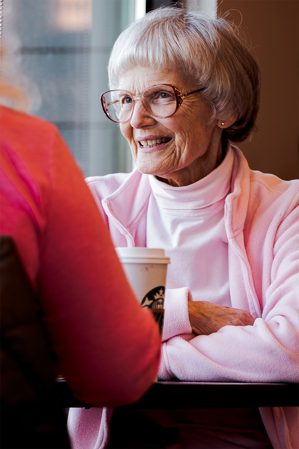 Older woman sitting across table talking with coffee