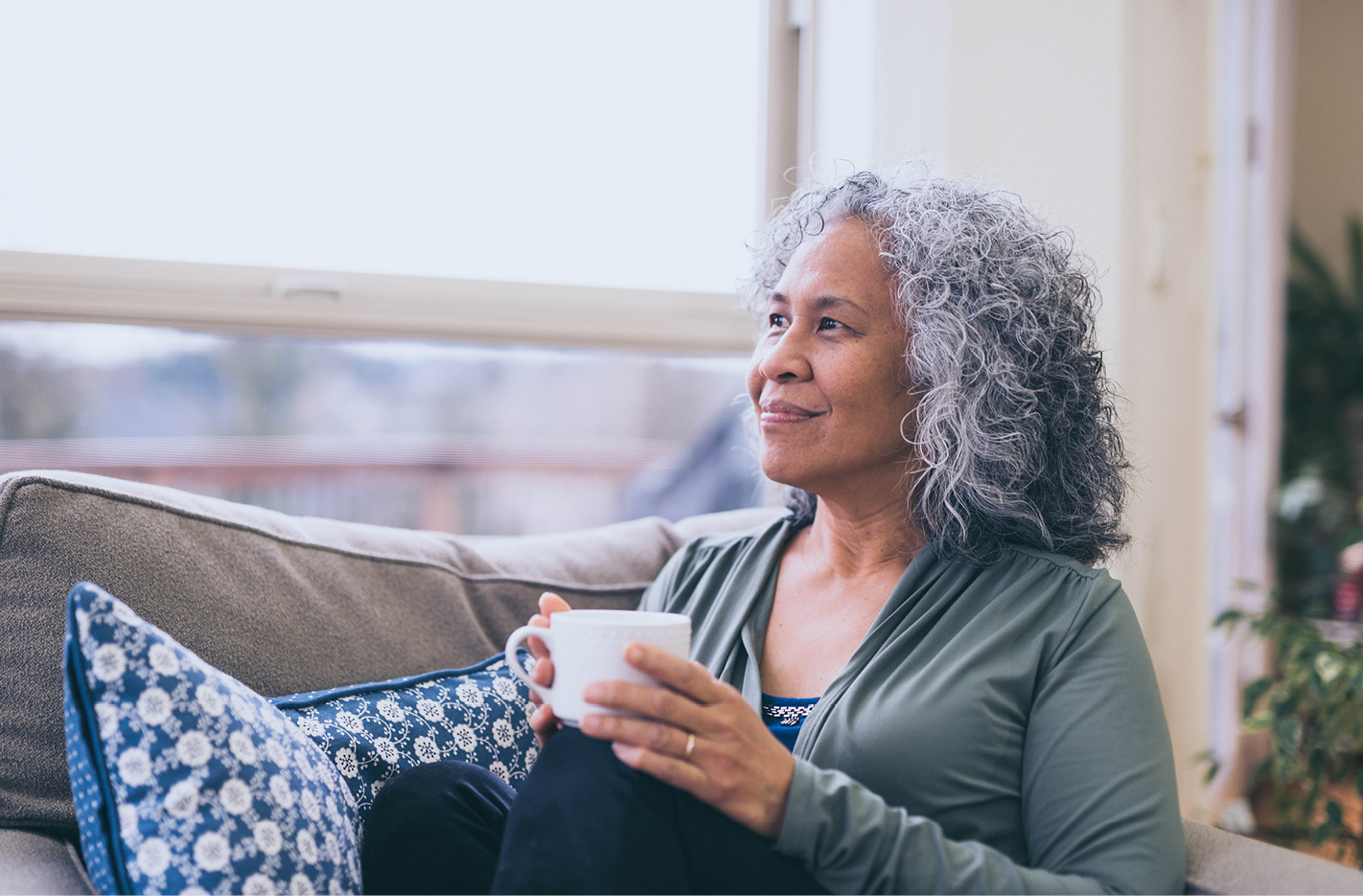 Older woman sitting on couch with coffee