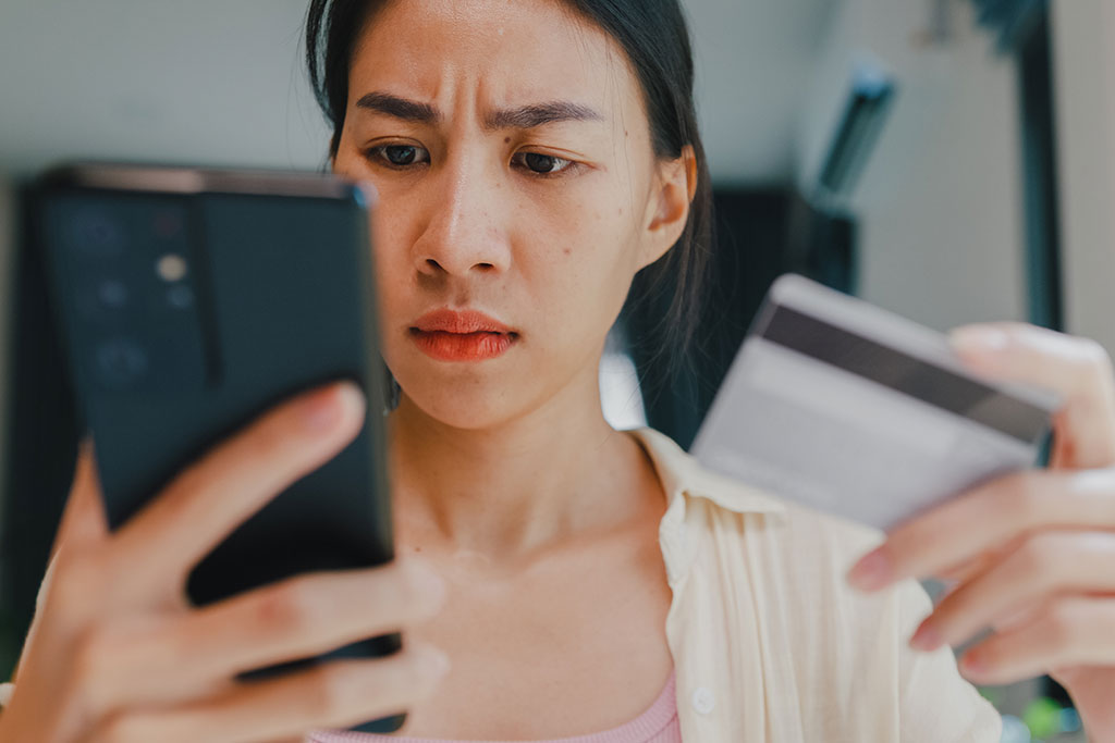 Concerned woman on cell phone holding credit card