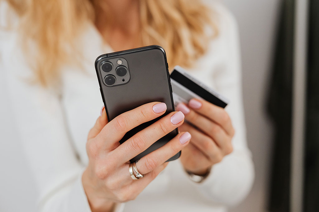Woman looking at phone holding credit card