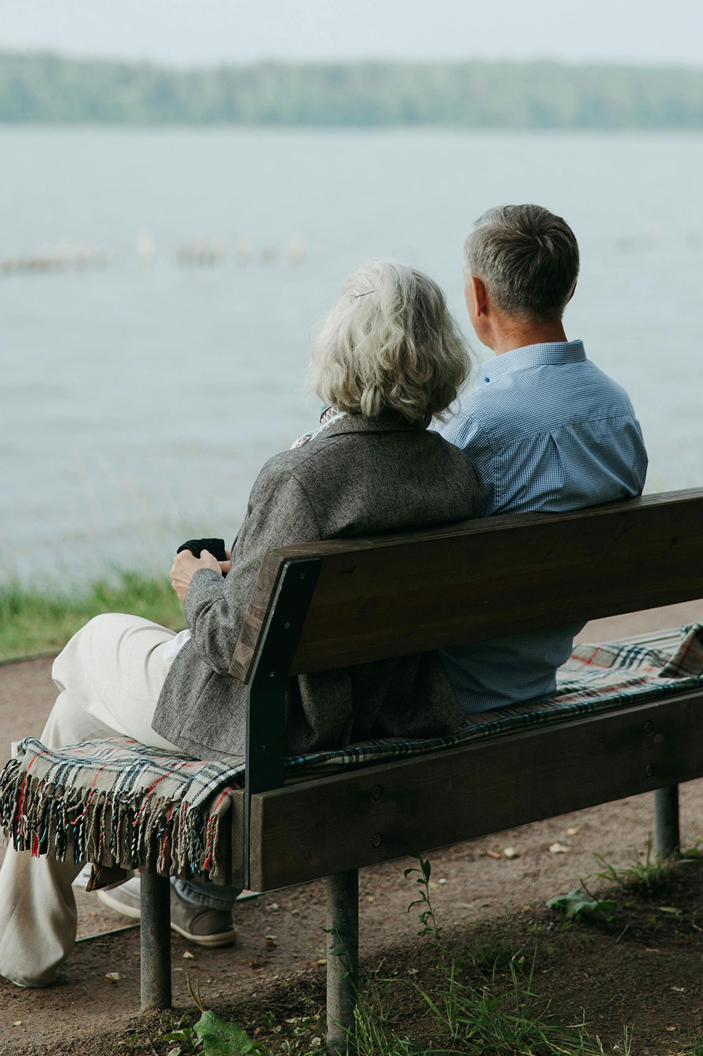 Older couple sitting on bench looking out at water