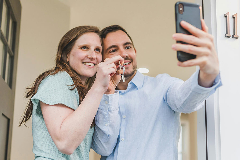 Happy couple taking a selfie with new keys to home