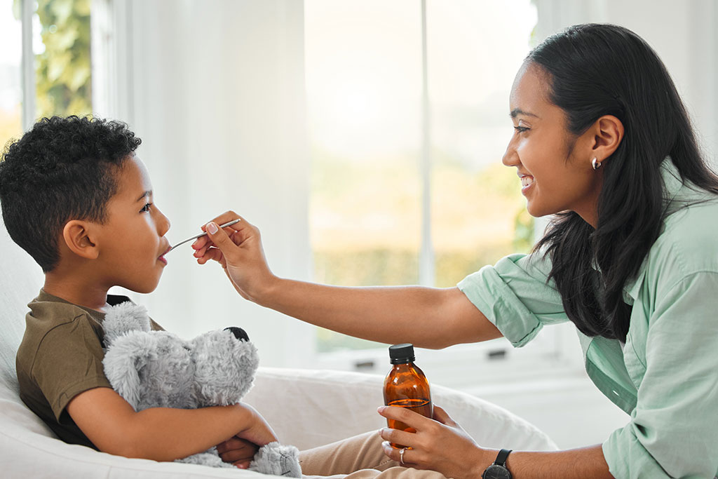 Younger mom giving little boy liquid medicine