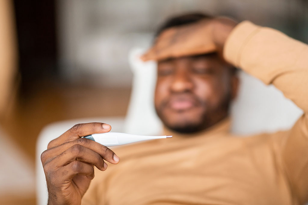 Man checking to see if he has a fever with thermometer