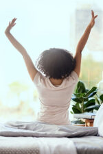 Woman waking up stretching in bed