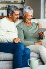 Older couple sitting on couch looking at tablet