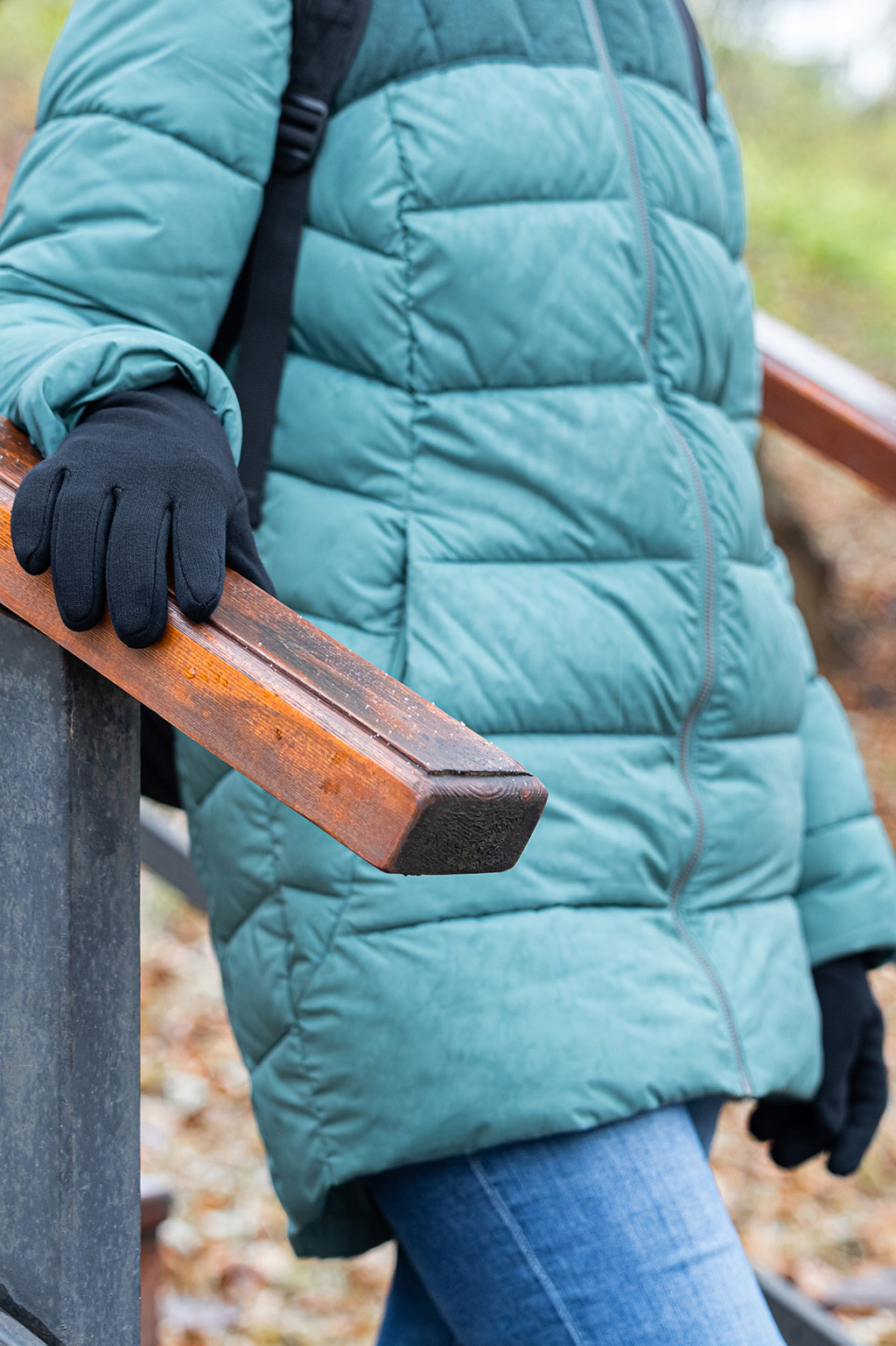 Person outside holding railing walking down steps in winter