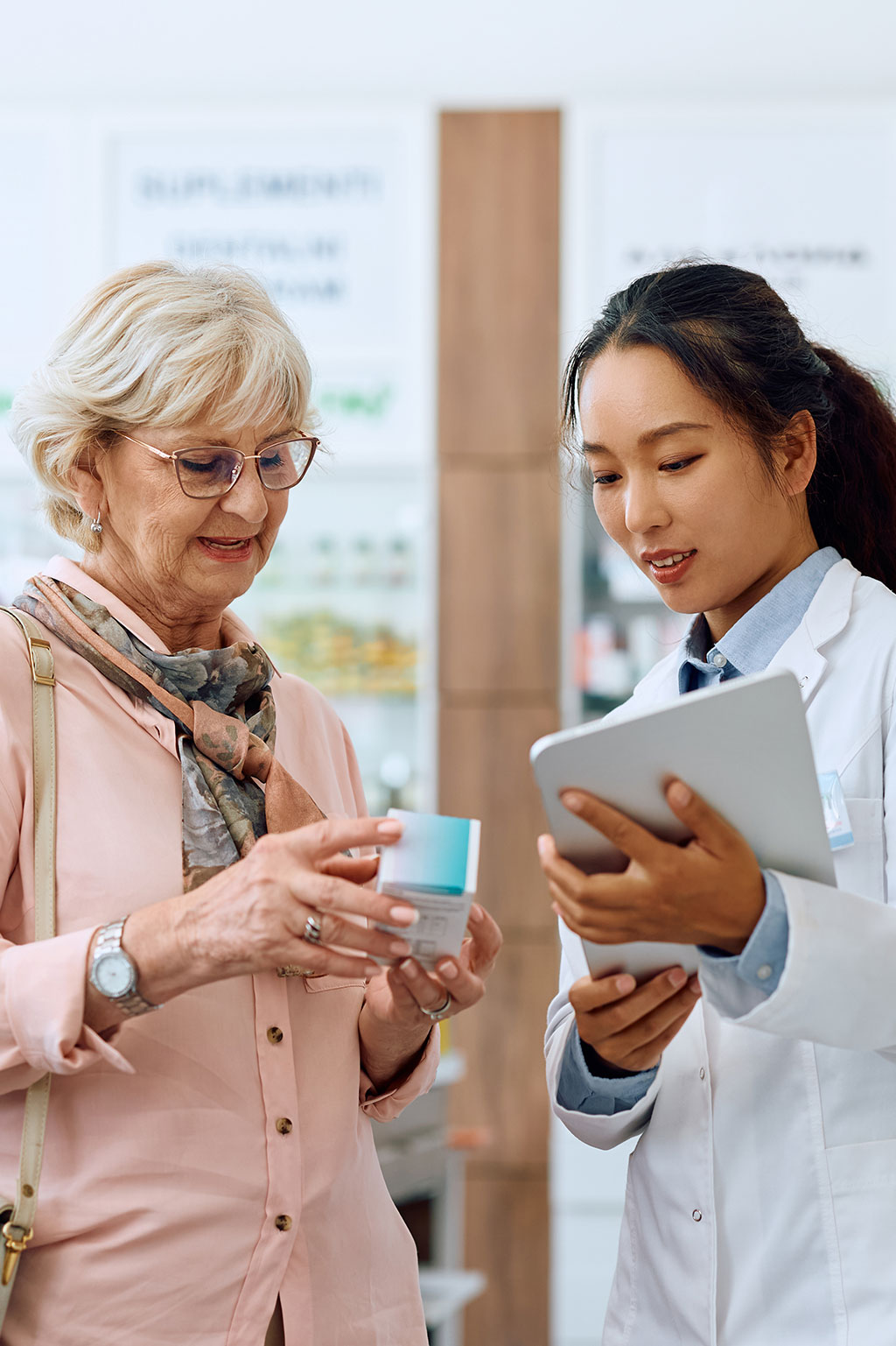 Pharmacists and older lady looking over medicine