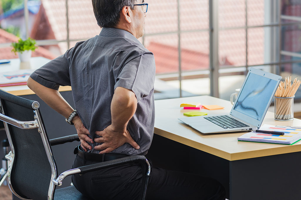 Man sitting at desk stretching back